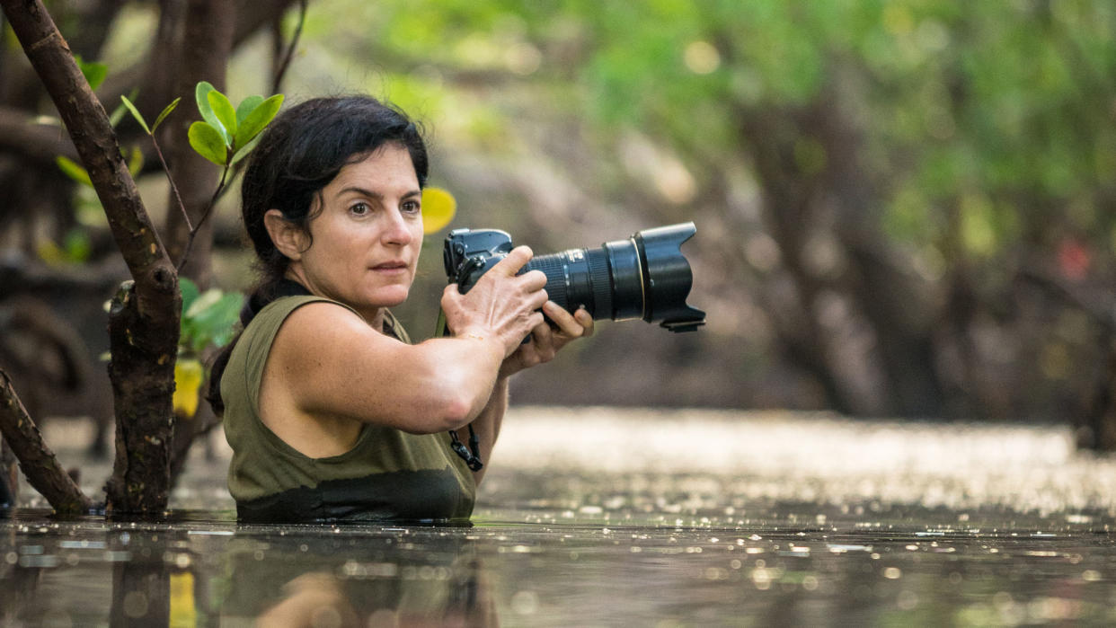  Image of a woman in some water with a camera. 