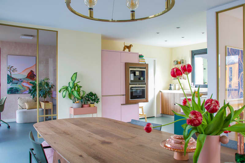 View of pastel kitchen from dining area with wood table.