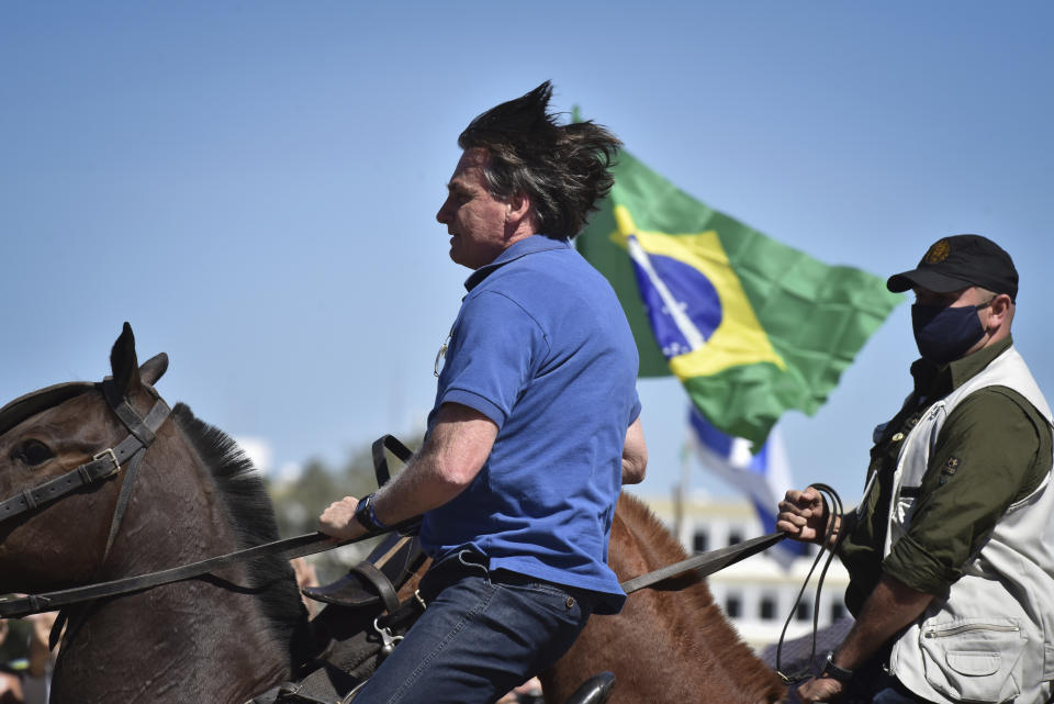 El presidente de Brasil, Jair Bolsonaro, monta un caballo de la policía para saludar a los partidarios reunidos afuera del palacio presidencial en Brasilia, el domingo 31 de mayo de 2020. (Foto AP/Andre Borges)