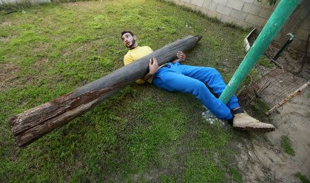 Palestinian Mohammad Baraka, 20, nicknamed by people as Gaza Samson, has a wooden pole placed over his stomach as he exercises in Deir al-Balah in the central Gaza Strip March 5, 2016. REUTERS/Mohammed Salem