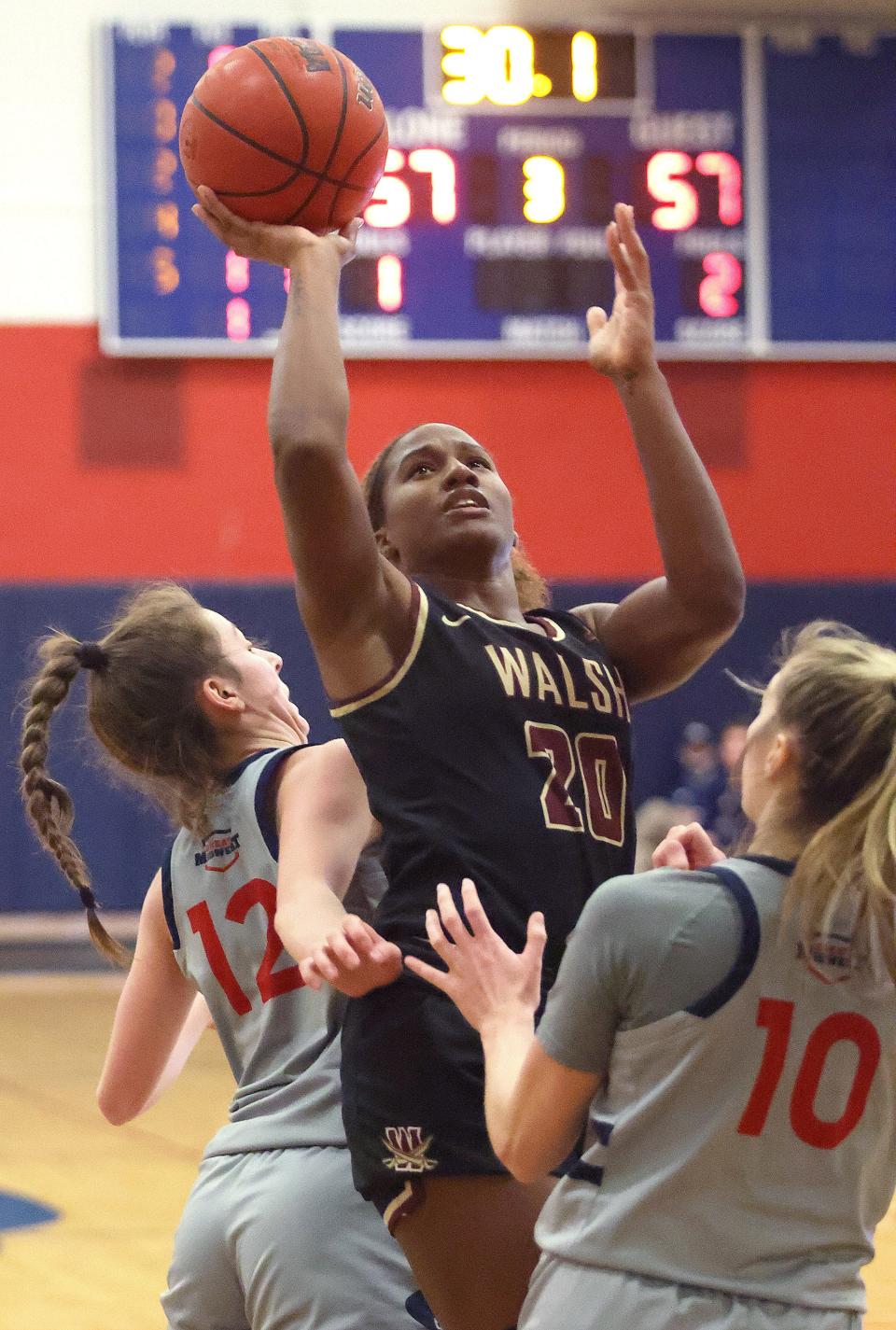 Walsh Cavaliers Sha Carter splits the defense of Malone’s Emma Kallas ,left, and Alexis Hutchison in the second half at Malone University Tuesday, December 14, 2021.