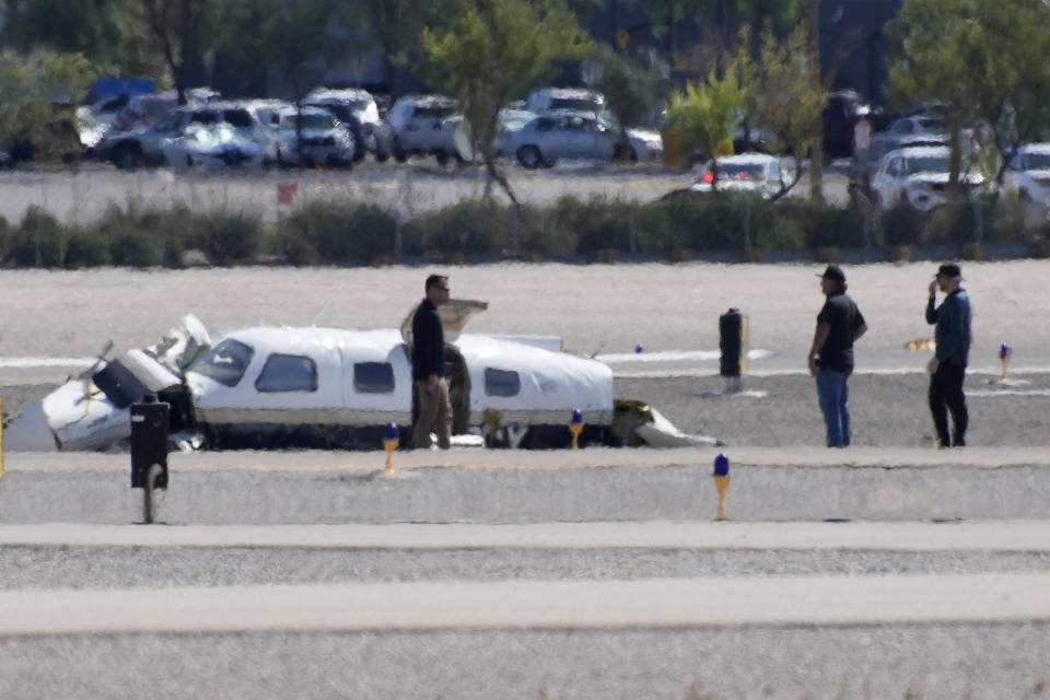 Officials investigate the wreckage of a plane at the site of a fatal crash at the North Las Vegas Airport, Sunday, July 17, 2022, in North Las Vegas, Nev. Authorities say several people are dead after two small planes collided at North Las Vegas Airport. (AP Photo/John Locher)