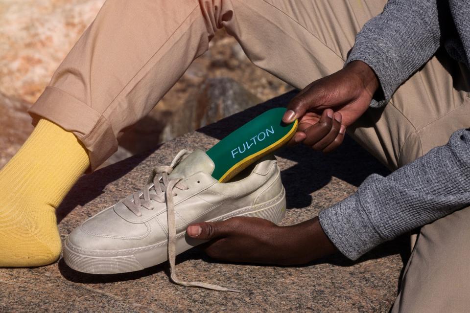 Person placing Fulton insoles into shoes.