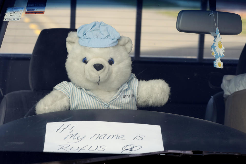 In this Tuesday, March 31, 2020, photo, a teddy bear sits on a the wheel of a car outside a house in Christchurch, New Zealand. New Zealanders are embracing an international movement in which people are placing teddy bears in their windows during coronavirus lockdowns to brighten the mood and give children a game to play by spotting the bears in their neighborhoods. (AP Photo/Mark Baker)