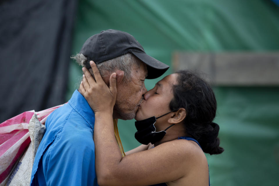 A couple kiss at the shelter where they live since losing their home in last year's hurricanes Eta and Iota, in La Lima, on the outskirts of San Pedro Sula, Honduras, Monday, Jan. 11, 2021. The devastation wrought by November's hurricanes and the economic damage of the COVID-19 pandemic has added to the forces of poverty and gang violence that drive Hondurans to migrate. (AP Photo/Moises Castillo)