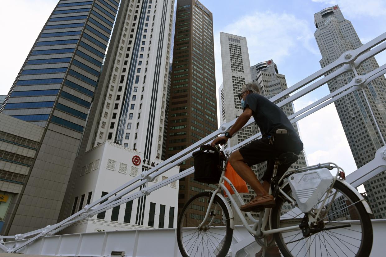 A man rides a bicycle past commercial buildings in the financial business district in Singapore on June 11, 2020, as the city state eased its partial lockdown restrictions aimed at curbing the spread of the COVID-19 coronavirus. (Photo by ROSLAN RAHMAN / AFP) (Photo by ROSLAN RAHMAN/AFP via Getty Images)