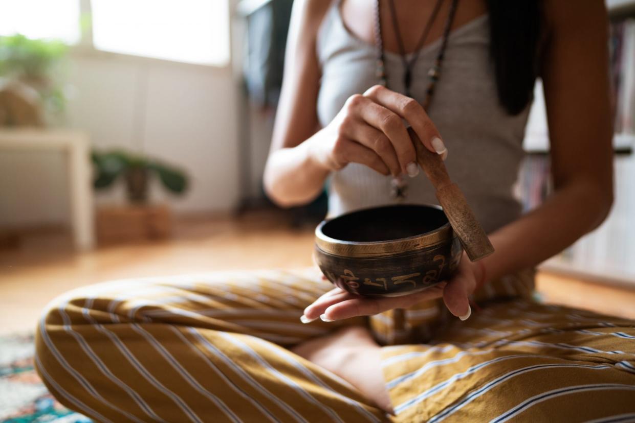 woman ringing Tibetan singing bowl as part of meditation