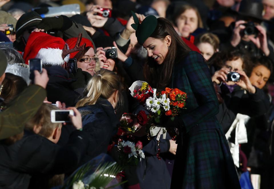 Britain's Catherine, the Duchess of Cambridge, receives flowers from well-wishers as she leaves a Christmas Day morning service at the church on the Sandringham Estate in Norfolk, eastern England, December 25, 2013. REUTERS/Andrew Winning (BRITAIN - Tags: ROYALS RELIGION)