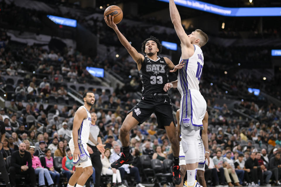 San Antonio Spurs' Tre Jones (33) goes to the basket against Sacramento Kings' Domantas Sabonis, right, during the second half of an NBA basketball game, Sunday, Jan. 15, 2023, in San Antonio. (AP Photo/Darren Abate)