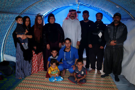 Displaced Iraqi Meshal Hadi (C), 65, poses for a photograph with his family inside their tent at Hammam al-Alil camp south of Mosul, Iraq, April 1, 2017. Hadi, a well-off businessman in his former life, said the family had to flee because of the shelling and the lack of water and electricity. He has no idea if his Mosul house is still standing; he lost contact with friends and neighbours. During the day, women keep the tent clean while men look for food. The family wants to go back home as soon as possible. REUTERS/Suhaib Salem SEARCH "DISPLACED REFUGE" FOR THIS STORY. SEARCH "WIDER IMAGE" FOR ALL STORIES.
