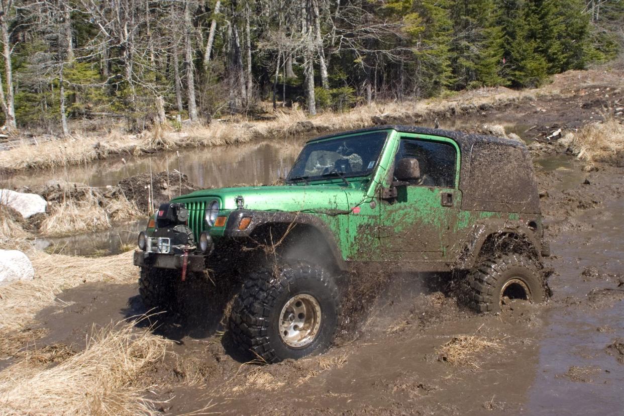 Bright green Jeep off-roading in mud.