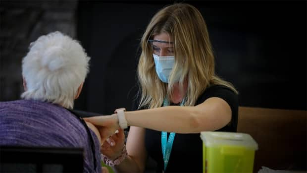 An Alberta Health Services worker gives a senior a vaccine shot. In Phase 1, Albertans born in 1946 or earlier can book an appointment online, call 811, or contact a participating pharmacy in Calgary, Edmonton or Red Deer.