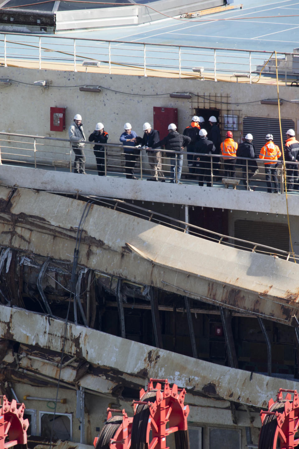 Captain Francesco Schettino, third from left, talks on the upper deck of the wreck of the Costa Concordia cruise ship, just off the coast of the Giglio island, Thursday, Feb. 27, 2014. The captain of the Costa Concordia has been permitted to go aboard the shipwreck for the first time since it capsized two years ago as part of a new court-ordered search. Consumer groups and lawyers for Capt. Francesco Schettino asked the court in Grosseto to authorize the searches to determine if any factors beyond human error contributed to the disaster. After searching the bridge and elevators last month, experts will examine the emergency generators Thursday. (AP Photo/Andrew Medichini)