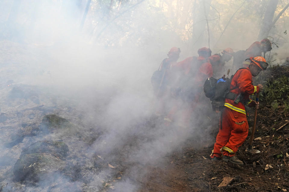 A California Dept. of Corrections fire crew cuts a containment line while fighting the CZU August Lightning Complex Fire on Friday, Aug. 21, 2020, in Bonny Doon, Calif. (AP Photo/Marcio Jose Sanchez)