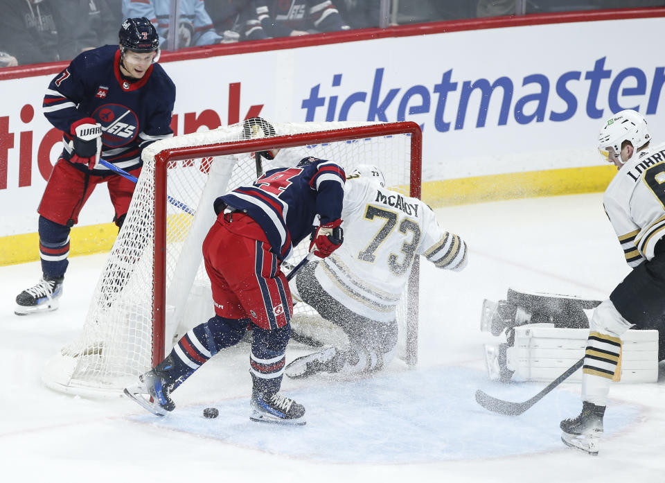 The puck goes off the skate of Winnipeg Jets' Josh Morrissey (44) and into the net as Boston Bruins' Charlie McAvoy (73) defends during the first period of an NHL hockey game Friday, Dec. 22, 2023, in Winnipeg, Manitoba. (John Woods/The Canadian Press via AP)