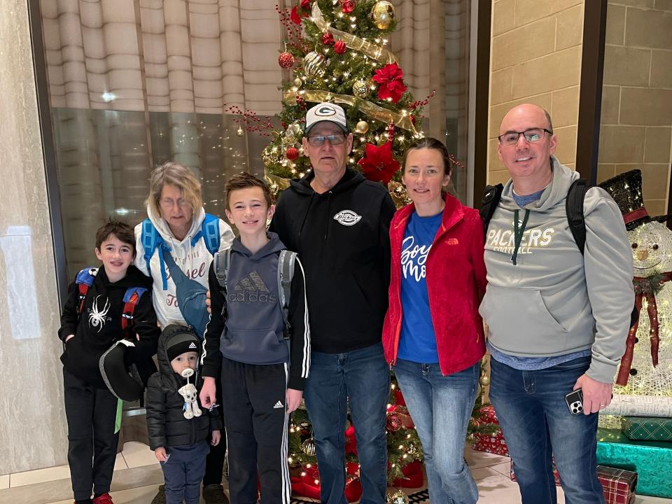 A family of 7 stands in front of a Christmas tree.