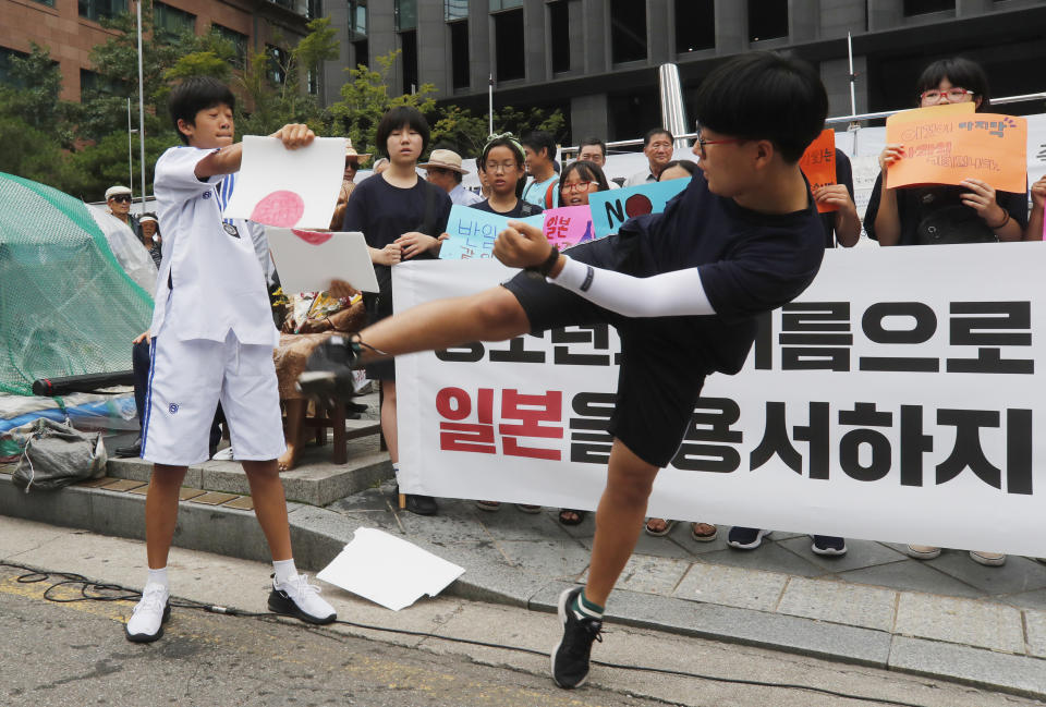 A South Korean elementary school student breaks a plastic plate showing a Japanese flag during a rally to denounce Japan's trade restrictions on South Korea in front of the Japanese embassy in Seoul, South Korea, Thursday, Aug. 8, 2019. Japan has granted the first permit for South Korea-bound shipment of chemicals for use in high-tech materials under Tokyo's new export requirement that has increased tensions with Seoul. (AP Photo/Ahn Young-joon)