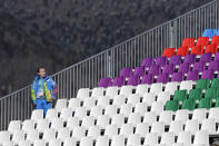 A volunteer stands in an empty grandstand during the women's snowboard slopestyle qualifying at the Rosa Khutor Extreme Park ahead of the 2014 Winter Olympics, Thursday, Feb. 6, 2014, in Krasnaya Polyana, Russia. (AP Photo/Andy Wong)