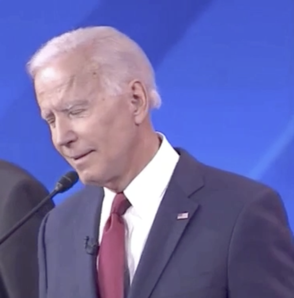 Joe Biden, wearing a suit and tie, speaks into a microphone on stage