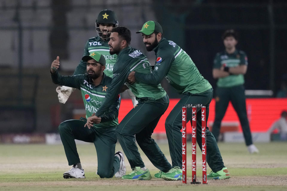 Pakistan's Babar Azam, left, and Shadab Khan, right, call for first aid after a ball hit on the finger of Mohammad Nawaz, center, during the third one-day international cricket match between Pakistan and New Zealand, in Karachi, Pakistan, Wednesday, May 3, 2023. (AP Photo/Fareed Khan)