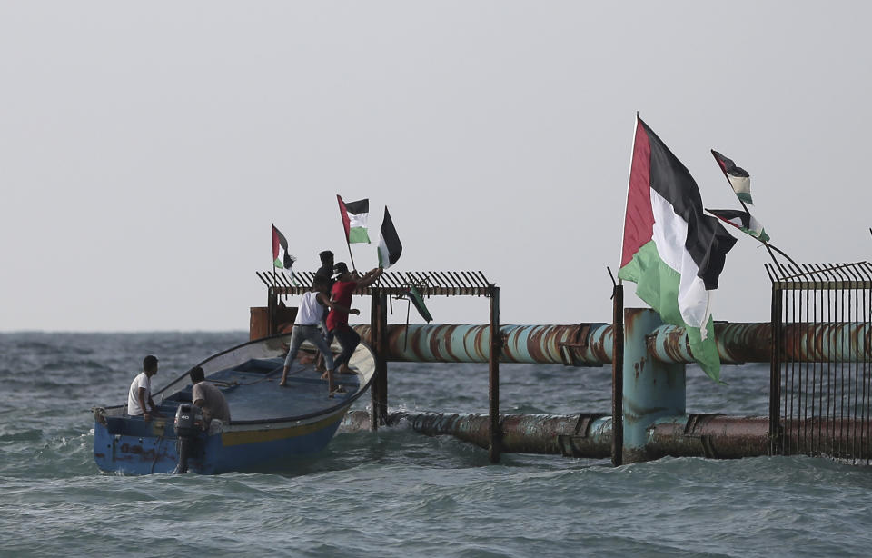 Palestinian protesters on fishing boats hang national flags at the border fence during a protest on the beach at the border with Israel near Beit Lahiya, northern Gaza Strip, Monday, Oct. 8, 2018.(AP Photo/Khalil Hamra)