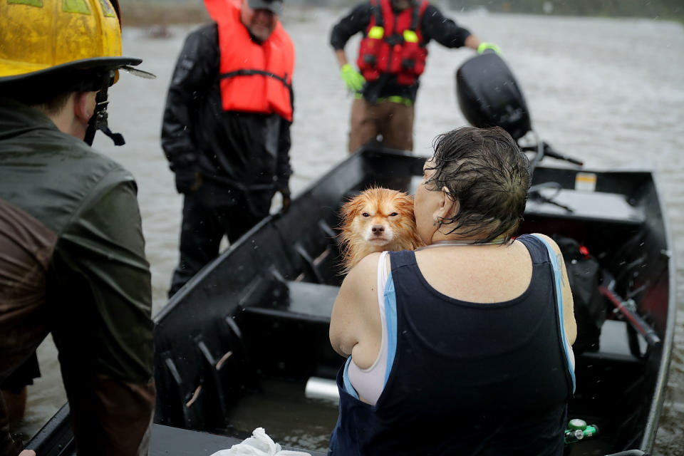 Rescue workers from Township No. 7 Fire Department and volunteers from the Civilian Crisis Response Team use a boat to rescue a woman and her dog from their flooded home.