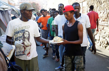 Migrants receive food from volunteers at a makeshift camp in Via Cupa (Gloomy Street) in downtown Rome, Italy, August 1, 2016. REUTERS/Max Rossi