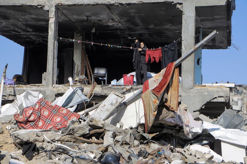 A Palestinian hangs clothes next to a destroyed building, in Jabalia refugee camp