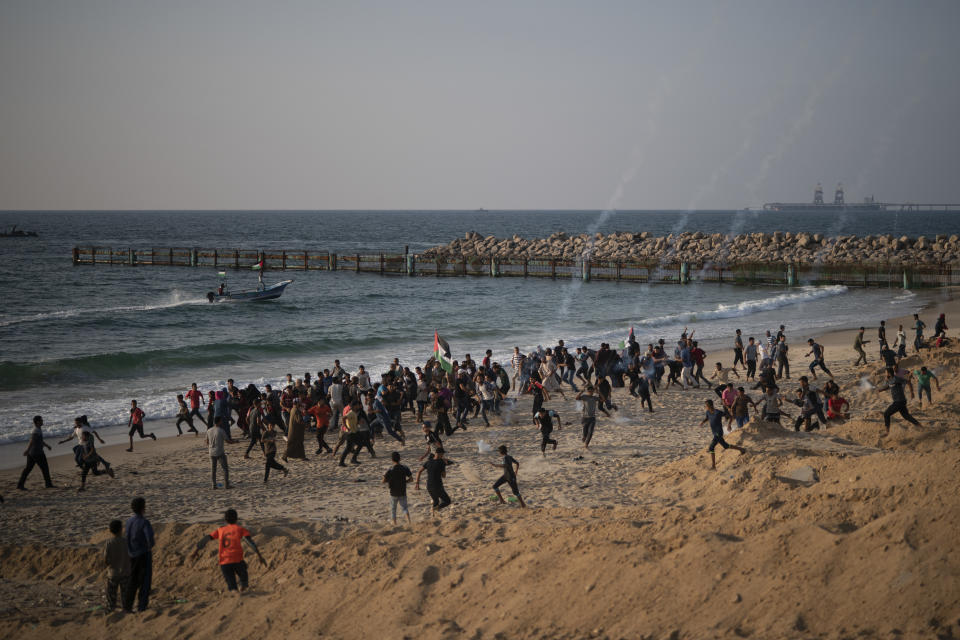 Palestinian protesters run from tear gas fired by Israeli soldiers during a protest on the beach near the border with Israel in Beit Lahiya, northern Gaza Strip, Sunday, Sept. 2, 2018. (AP Photo/Felipe Dana)