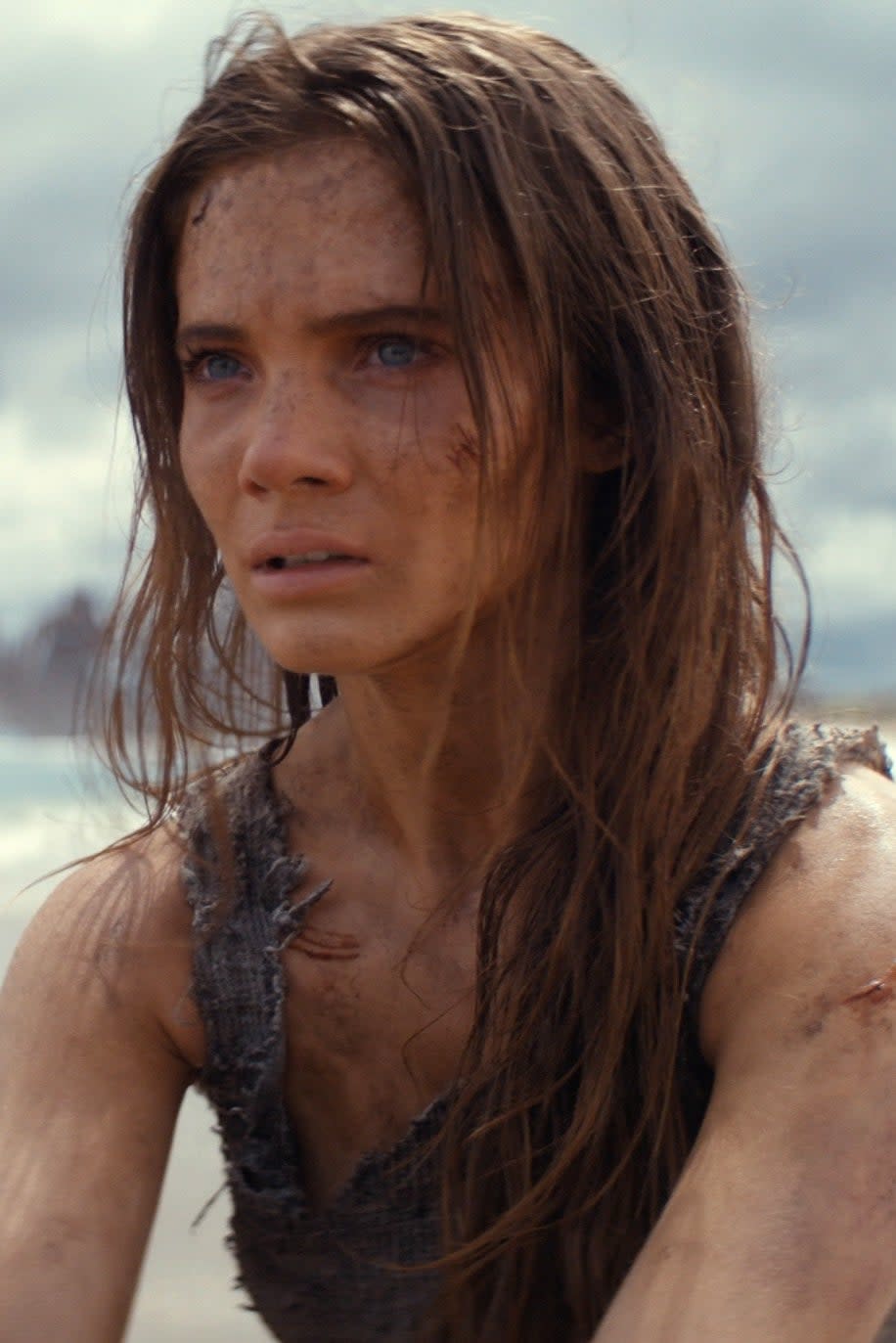 Freya Allan distressed on a beach with two horseback riders approaching in Kingdom of the Planet of the Apes