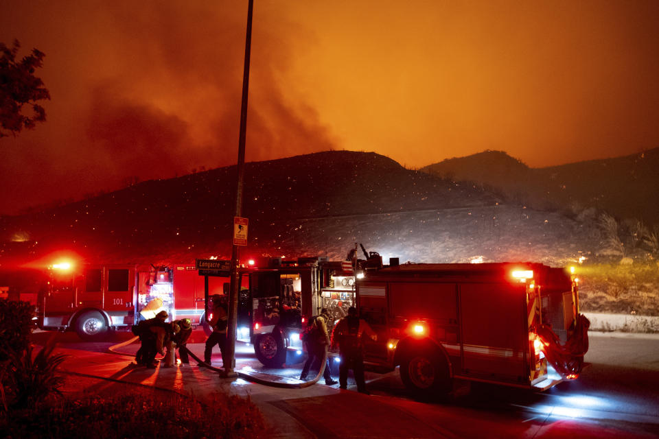 Firefighters refill their truck with water along Sesnon Boulevard early Friday morning, Oct. 11, 2019, as flames burn on the hills in Granada Hills, Calif. (Photo: David Crane/The Orange County Register via AP)