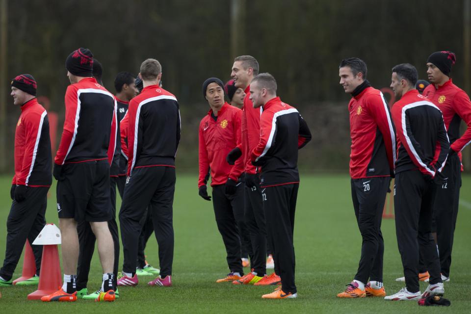 Manchester United's Shinji Kagawa, centre, looks on as teammate Nemanja Vidic, centre right, laughs during training session at Carrington training ground in Manchester, Monday, Feb.24, 2014. Manchester United will play Olympiakos in a Champions League first knockout round on Tuesday. (AP Photo/Jon Super)