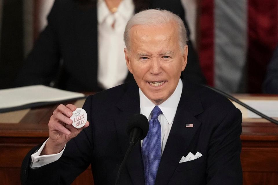 President Joe Biden holds a pin with the name of Laken Riley, a Georgia woman who was allegedly killed by a Venezuelan man. Republicans have used her her death to push for plans to militarize the US-Mexico border (AP)