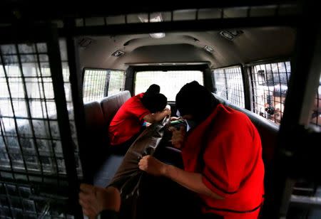 FILE PHOTO: Detainees hold items from a men's club in a police vehicle after the police conducted a weekend raid on what authorities described as a "gay spa" in Jakarta, Indonesia, October 9, 2017. REUTERS/Beawiharta/File Photo