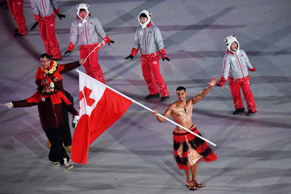 Flag bearer Pita Taufatofua of Tonga and teammates enter the stadium.