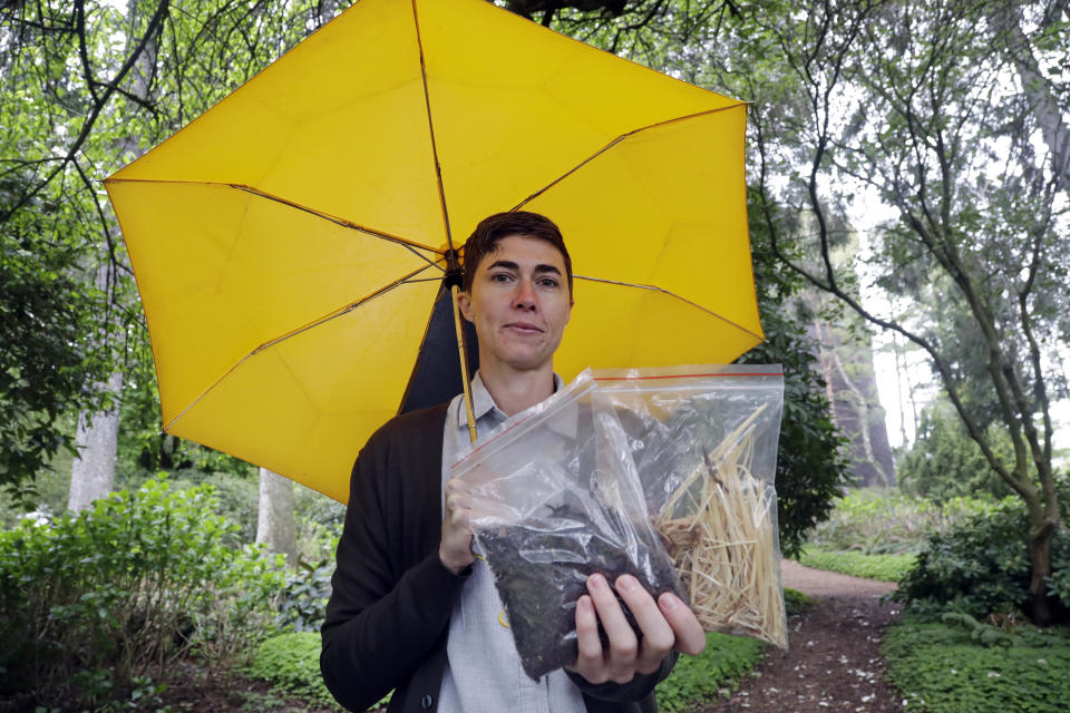 In this Friday, April 19, 2019, photo Katrina Spade, the founder and CEO of Recompose, displays a sample of the compost material left from the decomposition of a cow, left, and some of the combination of wood chips, alfalfa and straw used in the process, as she poses for a photo in Seattle. (AP Photo/Elaine Thompson)