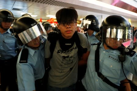 A protester is detained by the police officers at Amoy Plaza shopping mall in Kowloon Bay, Hong Kong