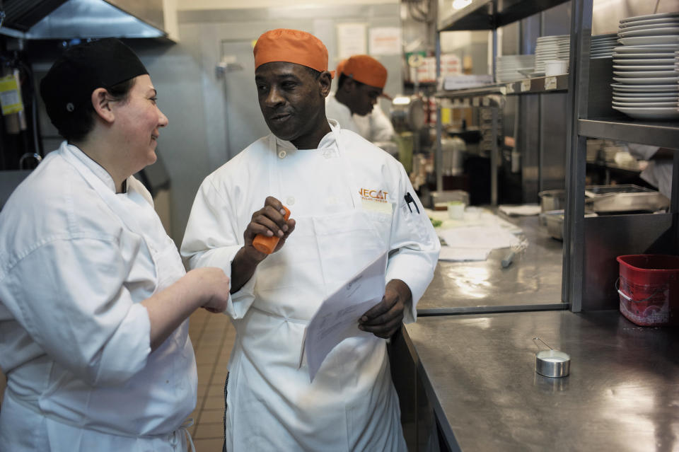 In this Tuesday, Oct. 2, 2018 photo Phillip Oliver, of New Bedford, Mass., right, in recovery from opioid addiction, speaks with chef and program director Jessica Asbun, of Brookline, Mass., left, in a culinary training program at the New England Center for Arts and Technology, in Boston. In Massachusetts, with Medicaid expansion already paying for opioid addiction treatment, emergency money from Congress goes largely toward recovery services. The state has chosen to use its federal money for those in long term recovery to pay for things like housing, and job training. (AP Photo/Steven Senne)