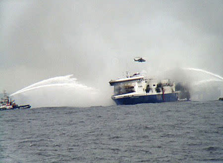 A rescue helicopter flies over the burning car ferry Norman Atlantic as fire fighting tug boats douche the vessel in south Adriatic sea December 28, 2014. REUTERS/Skai TV