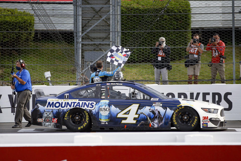 Kevin Harvick waves a checker flag for photographers after winning the NASCAR Cup Series auto race at Pocono Raceway, Saturday, June 27, 2020, in Long Pond, Pa. (AP Photo/Matt Slocum)