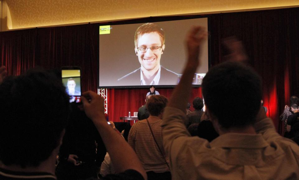 Supporters of Amnesty International cheer and shoot mobile phone videos as accused government whistleblower Edward Snowden is introduced via teleconference during the Amnesty International Human Rights Conference 2014 in Chicago, April 5, 2014. The video feed linked Snowden, who announcers said was somewhere in Russia, with the conference in Chicago. REUTERS/Frank Polich (UNITED STATES - Tags: POLITICS SOCIETY)