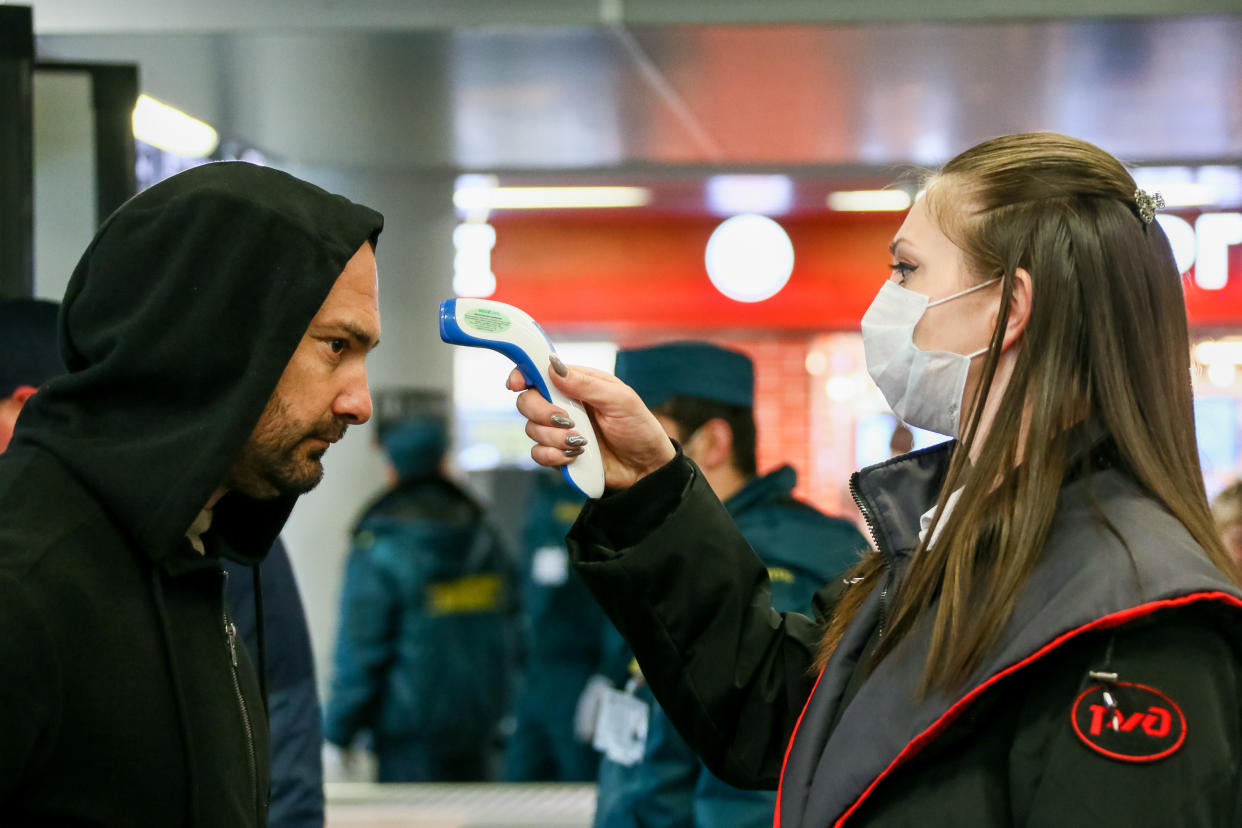 SOCHI, RUSSIA - MARCH 17, 2020: An RZD Russian Railways worker in a face mask scans a passenger's temperature using a digital forehead thermometer at the Adler Railway Station in the Black Sea resort of Sochi during the pandemic of the novel coronavirus (COVID-19). As of 17 March 2020, Russia has confirmed more than 100 cases of the novel coronavirus. Dmitry Feoktistov/TASS (Photo by Dmitry Feoktistov\TASS via Getty Images)