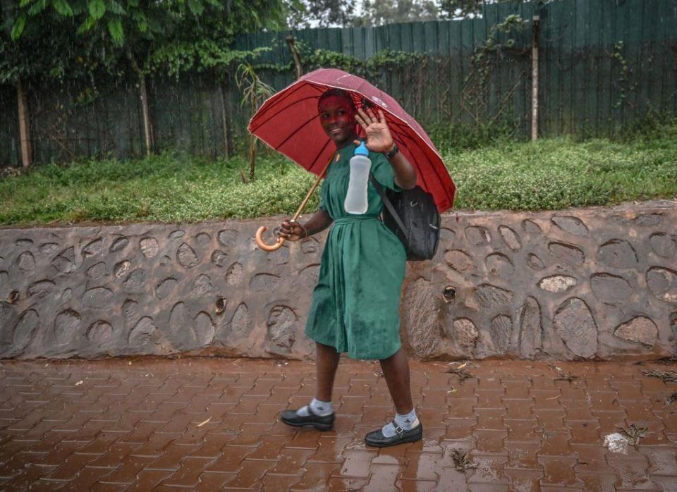 A girl dressed in a secondary school uniform walks in the rain in Kampala, Uganda, on Wednesday, July 24, 2024