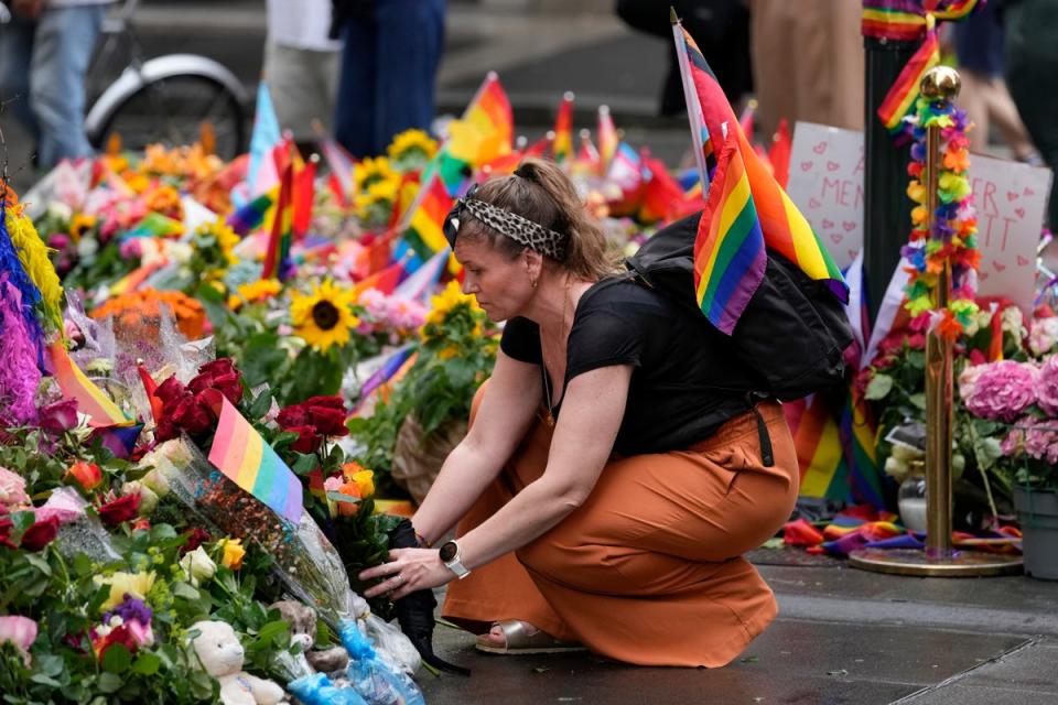 A woman lays flowers at the crime scene on Sunday (AP)