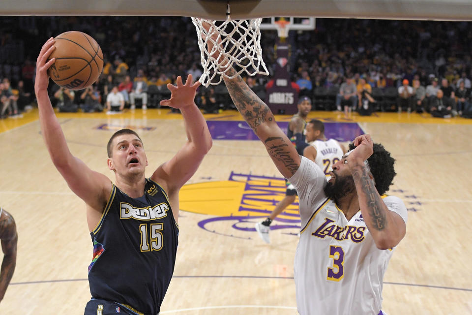 Denver Nuggets center Nikola Jokic, left, shoots as Los Angeles Lakers forward Anthony Davis defends during the first half of an NBA basketball game Sunday, April 3, 2022, in Los Angeles. (AP Photo/Mark J. Terrill)