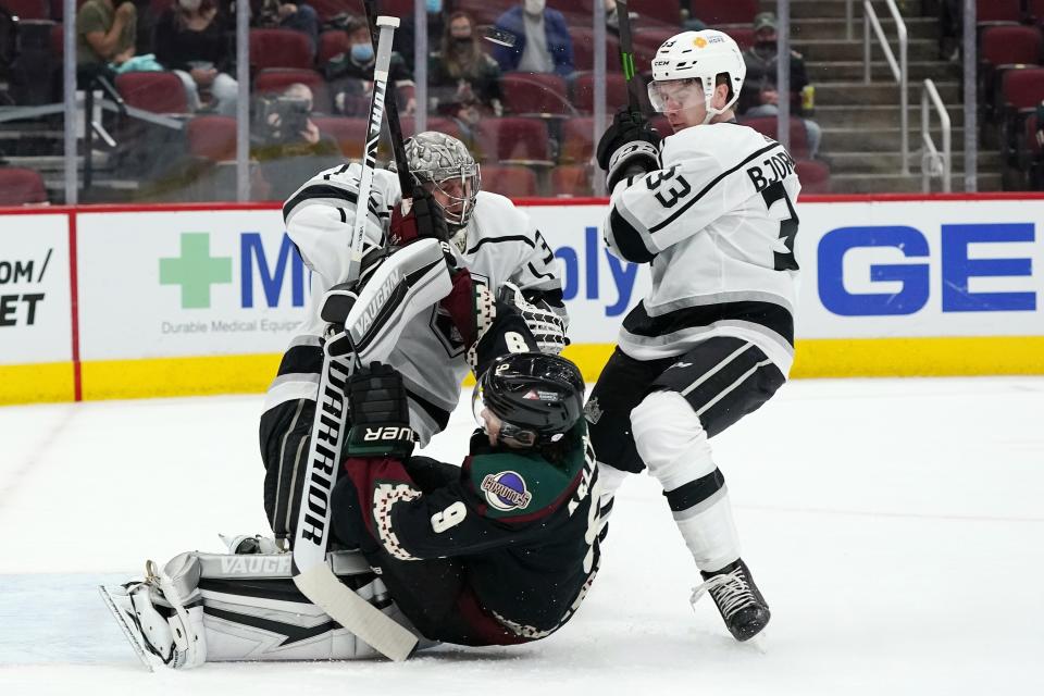 Arizona Coyotes right wing Clayton Keller (9) gets shoved into Los Angeles Kings goaltender Jonathan Quick, left, by Kings defenseman Tobias Bjornfot (33) during the first period of an NHL hockey game Monday, May 3, 2021, in Glendale, Ariz. (AP Photo/Ross D. Franklin)