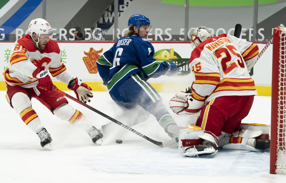 Calgary Flames defenseman Nikita Nesterov (89) defends as Vancouver Canucks right wing Brock Boeser (6) shoots onFlames goaltender Jacob Markstrom (25) during the second period of an NHL hockey game Thursday, Feb. 11, 2021, in Vancouver, British Columbia. (Jonathan Hayward/The Canadian Press via AP)