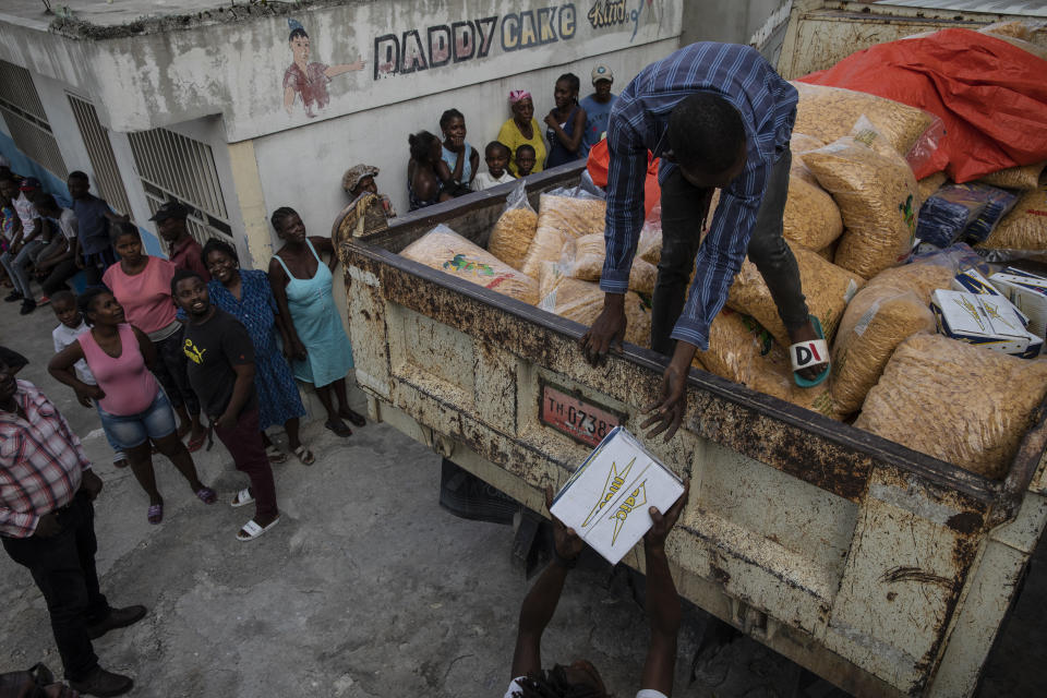 A worker stands on a truckload of corn flakes donated from the AAA political party to residents in the gang-controlled Bel Air neighborhood of Port-au-Prince, Haiti, Tuesday, Oct. 5, 2021. "It is a donation from the political party to a neighborhood. ... It is populism, but people are hungry. There is nothing wrong in giving them food." rationalizes Youri Mevs, campaign manager for the AAA's presidential candidate and businesswoman who is being extorted for 500,000 dollars by the G9 gang coalition. Mevs chose not to pay the extortion. Instead she gave the order to one of her managers: "Get them corn flakes, milk, pasta, tomato and soap." (AP Photo/Rodrigo Abd)
