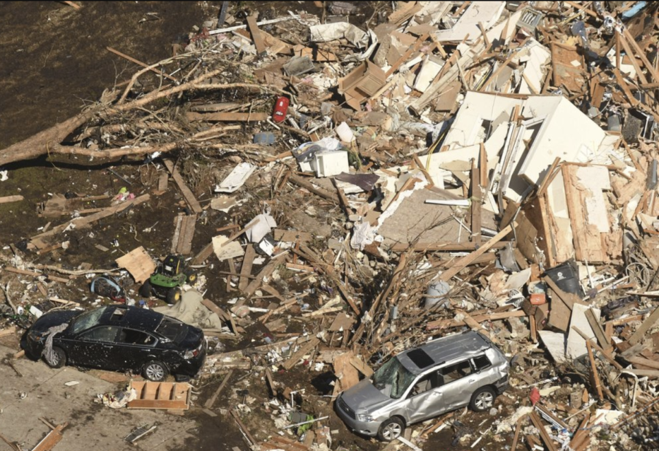 Houses flattened by the tornado and two crumpled cars. 