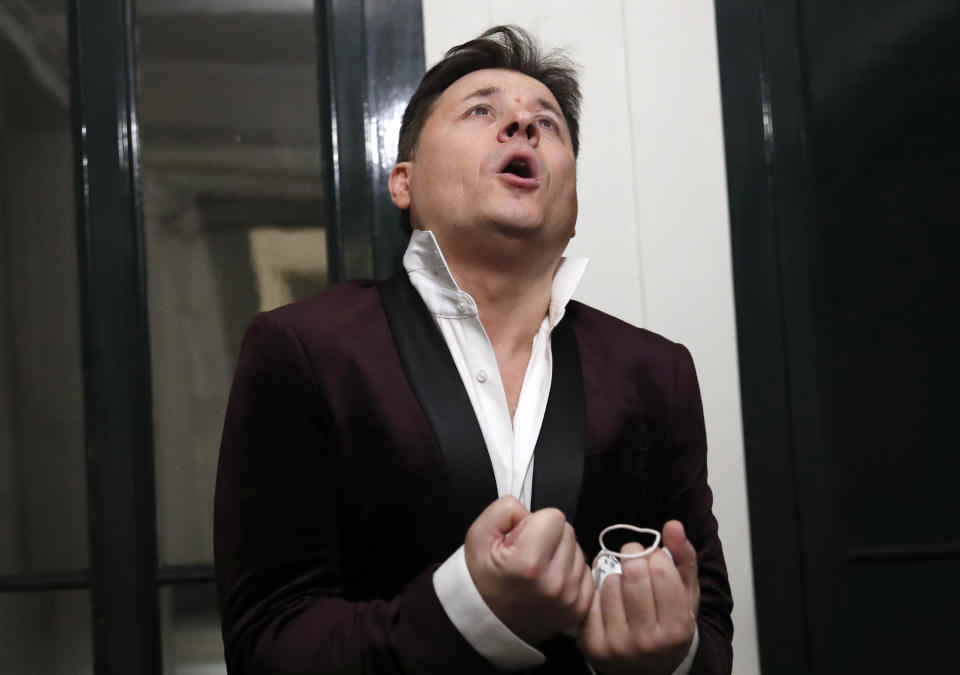 FILE - French tenor singer Stephane Senechal performs after he sings at dusk, the U.S. national anthem and Tosca of Puccini, from his apartment window during the monthlong partial lockdown to stop fast-rising virus hospitalizations and deaths, in Paris, Nov. 09, 2020. Senechal, along with professional and amateur musicians, sang from their balconies or windows to uplift neighbors. (AP Photo/Francois Mori, File)